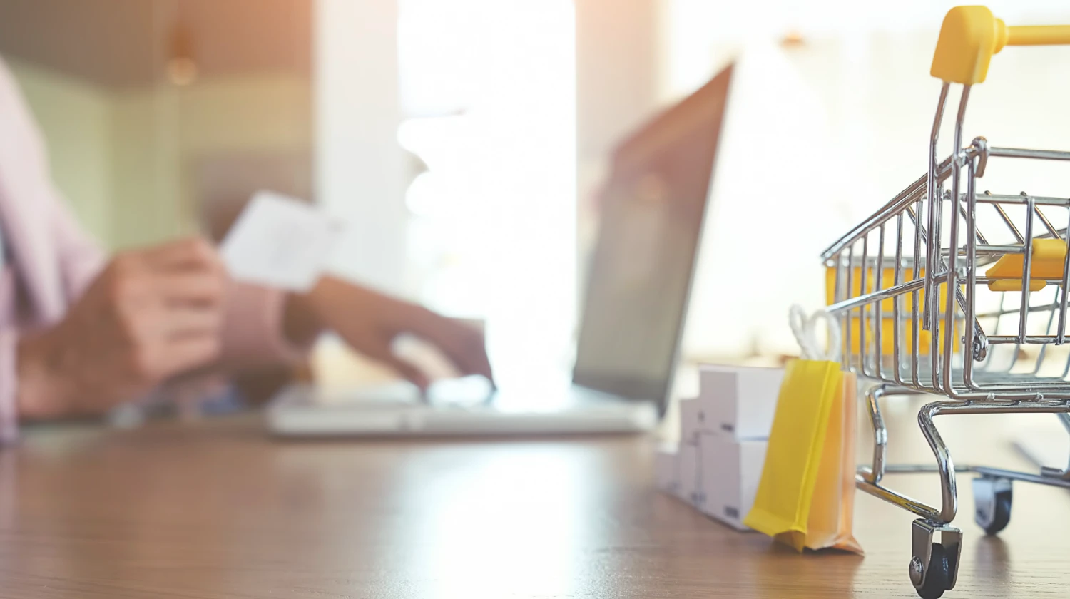 Um homem no computador com um carrinho de compras na mesa simbolizando um ecommerce da loja integrada